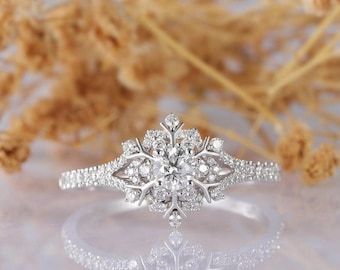 May include: A silver snowflake engagement ring with a round center stone and smaller stones set in the snowflake design.