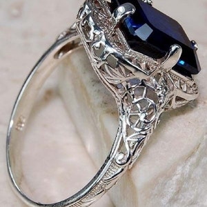 May include: A silver ring with a large, dark blue gemstone set in a filigree design.