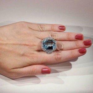 May include: A large, rectangular aquamarine gemstone ring set in silver with a halo of smaller diamonds.