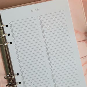 Puede incluir: Una página de lista de tareas blancas con un encabezado negro que dice "TO DO LIST". La página está dividida en dos columnas, cada una con una lista de líneas en blanco y casillas de verificación.