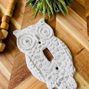 May include: White ceramic owl light switch cover with a distressed finish. The owl has a detailed design and a single light switch opening.