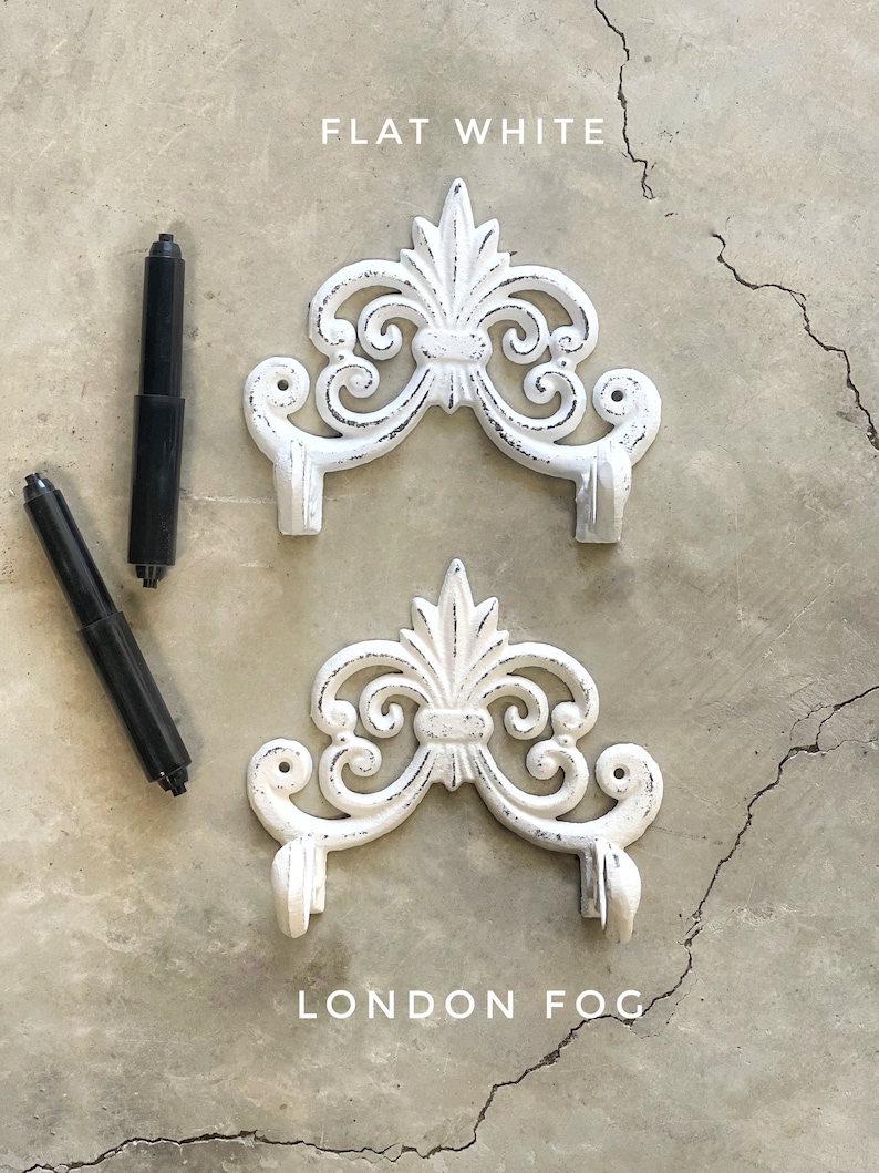 May include: Two white cast iron wall hooks with a decorative scroll design. The top hook is labeled "FLAT WHITE" and the bottom hook is labeled "LONDON FOG".