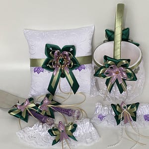 May include: A wedding set including a ring cushion, basket, cake server, and garters. Each item is decorated with green and purple ribbons and a jewel. The basket and garters have white lace trim.