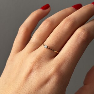 14k solid gold ring with a 4 prong set 0.10 carat 3 mm diamond .perfect as an everyday and stacking options, minimalistic promise ring displayed on a model