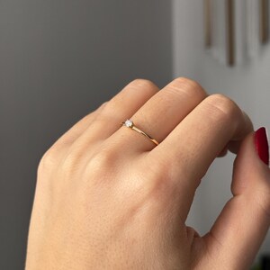 14k solid gold ring with a 4 prong set 0.10 carat 3 mm diamond .perfect as an everyday and stacking options, minimalistic promise ring displayed on a model side view