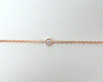 May include: A delicate rose gold chain bracelet with a single, clear diamond set in the center.