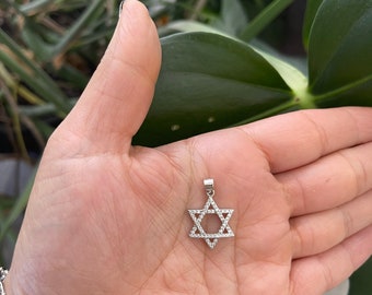 May include: A silver pendant in the shape of a Star of David, with small clear stones set around the edges.