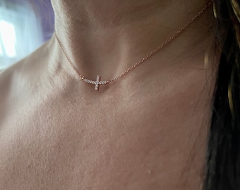 May include: A delicate rose gold necklace with a small, sparkling diamond cross pendant.