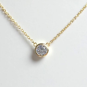 May include: A delicate gold chain necklace with a single round clear stone pendant.