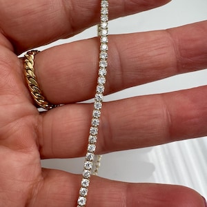 May include: A gold chain with small, clear stones set in a row. The chain is about 18 inches long.