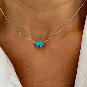 May include: A silver chain necklace with a small turquoise blue opal elephant pendant.