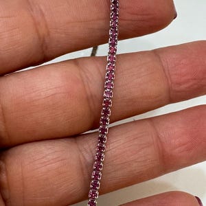 Könnte beinhalten: Ein zartes silbernes Kettenarmband mit kleinen rosafarbenen Edelsteinen, die in Pavé-Fassung gefasst sind.