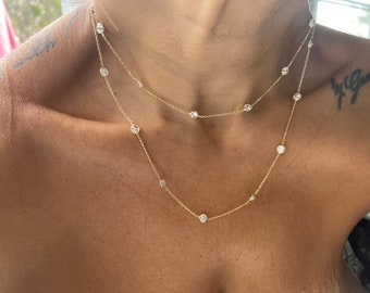 May include: A gold chain necklace with small, clear stones. The necklace is layered with two chains, one shorter than the other.