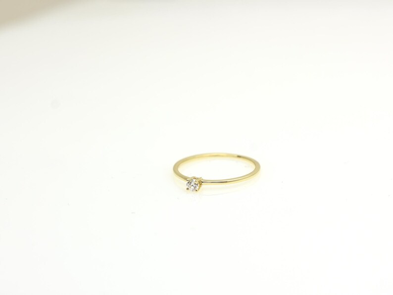14k solid gold ring with a 4 prong set 0.10 carat 3 mm diamond .perfect as an everyday and stacking options, minimalistic promise ring displayed on a white background