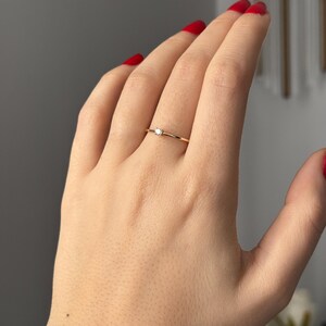 14k solid gold ring with a 4 prong set 0.10 carat 3 mm diamond .perfect as an everyday and stacking options, minimalistic promise ring displayed on a model