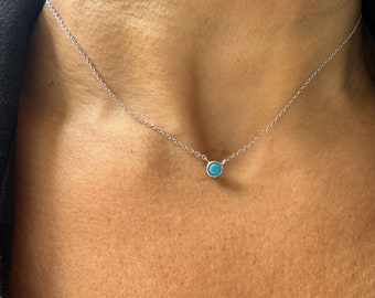 Può includere: Una collana a catena d'argento con un piccolo ciondolo rotondo in turchese.