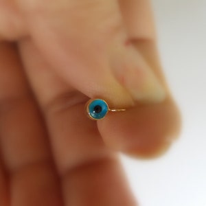 以下が含まれることがあります： 青い邪悪な目をモチーフにした金のリング。指につけられています。