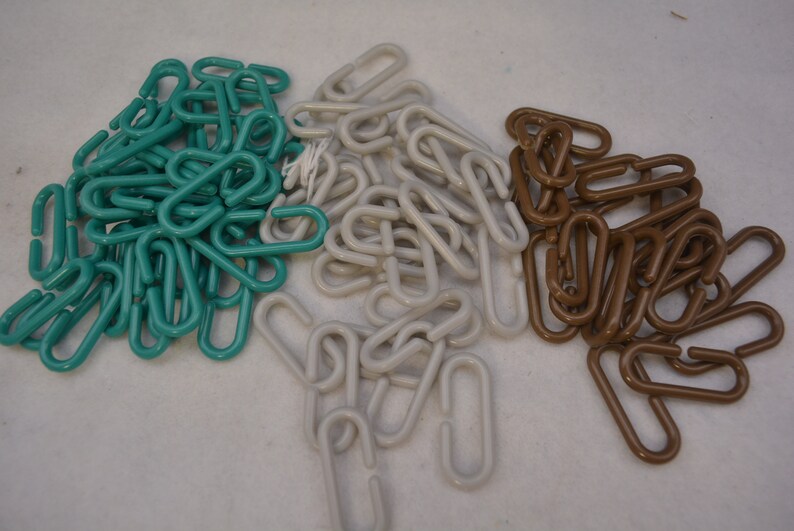 Puede incluir: Un mont&oacute;n de eslabones de cadena de pl&aacute;stico de color verde azulado, blanco y marr&oacute;n. Los eslabones son todos del mismo tama&ntilde;o y forma, y est&aacute;n dispuestos en un orden aleatorio.