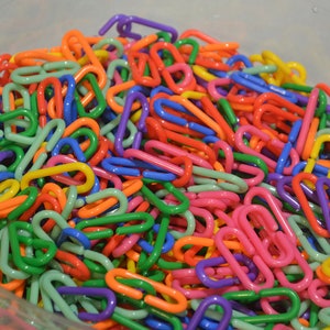 Puede incluir: Un taz&oacute;n grande lleno de eslabones de cadena de pl&aacute;stico de colores. Los eslabones son de varios colores, incluyendo rojo, naranja, amarillo, verde, azul, morado y rosa.
