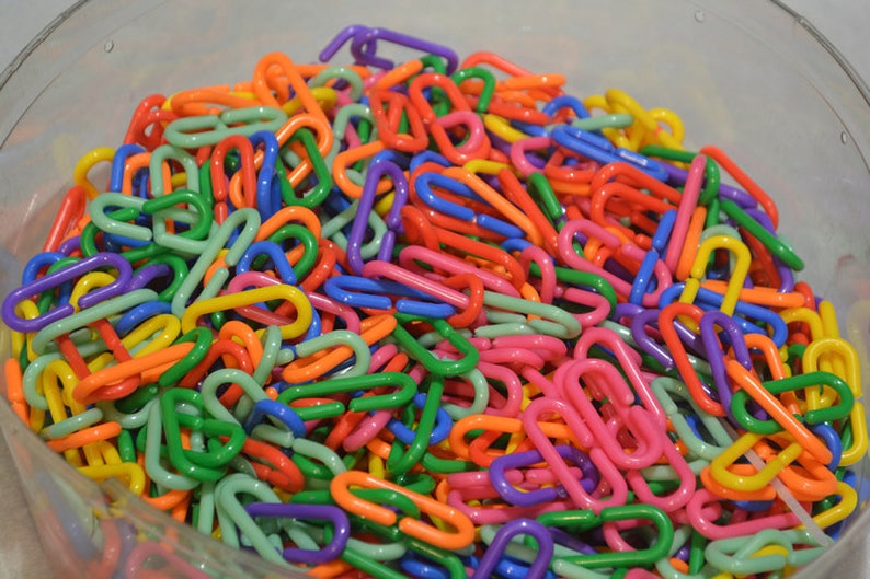Puede incluir: Un taz&oacute;n grande lleno de eslabones de cadena de pl&aacute;stico de colores. Los eslabones son de varios colores, incluyendo rojo, naranja, amarillo, verde, azul, morado y rosa.