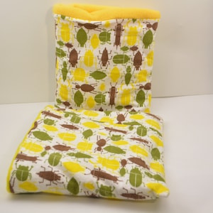 May include: Two rectangular cushions with a white background and a pattern of yellow, brown and green beetles. The cushions have a yellow border.