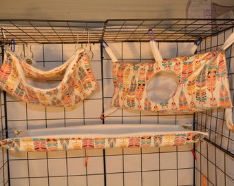 May include: Three colorful hanging beds for small pets, made of fabric with a feather pattern. The beds are suspended from a wire cage.
