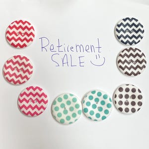 May include: A collection of decorative buttons with various patterns, including red and white zigzags, teal polka dots, and black and white zigzags. The handwritten text "Retirement SALE" is also visible.