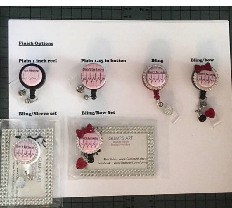 Puede incluir: Una variedad de opciones de carretes de insignia con diferentes acabados. Los carretes presentan un dise&ntilde;o rosa y blanco con el texto "Don't be tachy" y un gr&aacute;fico de ritmo card&iacute;aco. Los acabados incluyen carrete simple de 2,5 cm, bot&oacute;n simple de 3,175 cm, bling, bling/lazo y bling/manga.