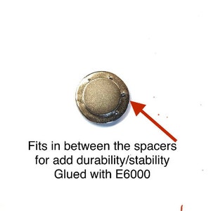 Pode incluir: Um disco de metal prateado com um centro elevado. O disco &eacute; projetado para caber entre os espa&ccedil;adores para maior durabilidade e estabilidade. O texto "Colado com E6000" est&aacute; escrito abaixo do disco.