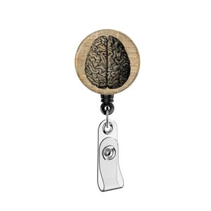 May include: A round, wooden badge reel featuring a detailed illustration of a human brain. The brain image is in black and white, set against a background of aged paper. The reel has a black cord and a silver-colored clip.