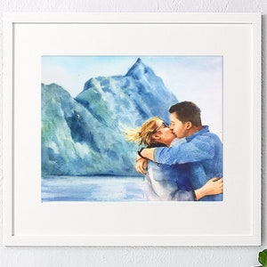 May include: Watercolor painting of a couple kissing in front of a mountain range. The couple is wearing casual clothing and the background is a blue and green watercolor wash.
