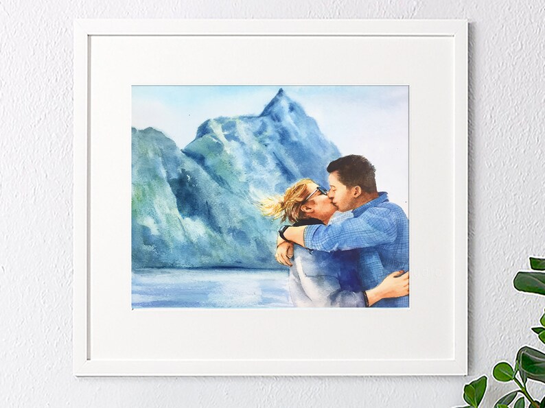 May include: Watercolor painting of a couple kissing in front of a mountain range. The couple is wearing casual clothing and the background is a blue and green watercolor wash.
