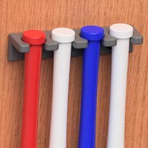 May include: A gray wall-mounted baseball bat holder with four bats. The bats are red, white, blue, and white.