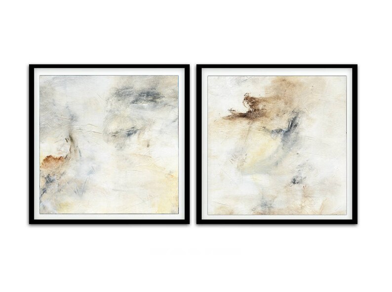 May include: Two abstract paintings in black frames. The paintings are both white with subtle shades of brown, gray, and yellow. The paintings are both abstract and feature brushstrokes and textures.