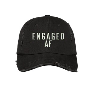 May include: Black distressed baseball cap with white embroidered text that reads "ENGAGED AF".