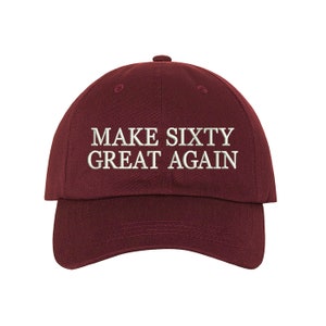 May include: Burgundy baseball cap with white embroidered text that reads "Make Sixty Great Again".