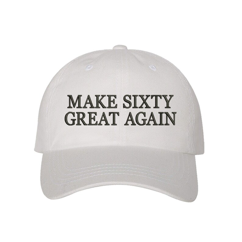 May include: White baseball cap with black embroidered text that reads "Make Sixty Great Again".