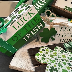 May include: A set of three wooden blocks with green shamrock designs and the text "Luck of the Irish", "Lucky Clover", and "Irish". The blocks are decorated with green and white ribbon and a green shamrock.