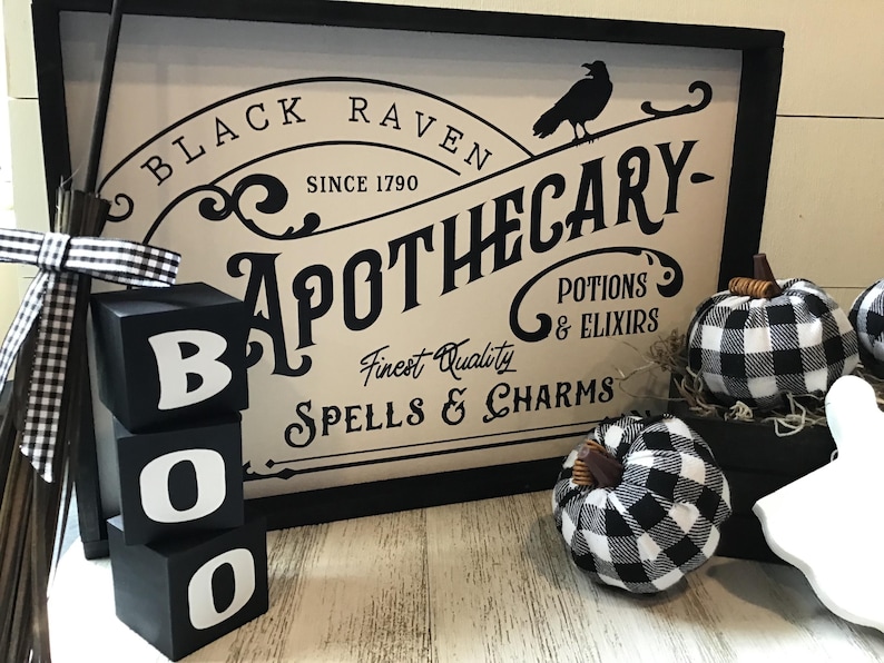 May include: Black and white wooden blocks spelling "BOO" with a sign that reads "Black Raven Apothecary - Finest Quality Spells & Charms - Potions & Elixirs" and black and white checkered pumpkins.