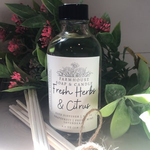 May include: A clear glass bottle with a black lid filled with a green liquid. The bottle has a white label with black text that reads "FARMHOUSE SOAP & CANDLE Fresh Herbs & Citrus REED DIFFUSER | Grapefruit | Fresh Mint | Lavender 4.0 OZ (118 ml)"