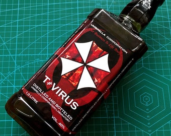 May include: A clear glass bottle with a black label that says "T-Virus" and "Umbrella Corporation Laboratory". The label also features a red and black umbrella logo with the text "Our Business Is Life Itself..." The bottle is 1.0 liter and 40% alcohol.