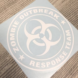 Puede incluir: Pegatina de vinilo blanco con un símbolo de riesgo biológico en el centro y el texto "Zombie Outbreak Response Team" alrededor del símbolo.