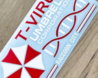Könnte beinhalten: Ein weißer Aufkleber mit rotem Text und einem roten und weißen Regenschirm-Motiv. Der Text lautet "T-Virus Umbrella Corporation Raccoon City". Der Aufkleber zeigt ein DNA-Doppelhelix-Motiv.