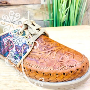 Pu&ograve; includere: Scarpe in pelle marrone con ricami floreali e suola intrecciata. Le scarpe hanno un pannello in tessuto colorato sul retro.