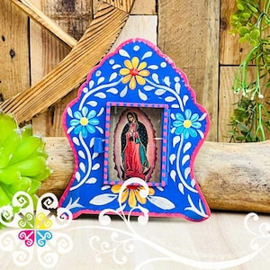 May include: A vibrant blue, hand-painted wooden frame with a religious image. The frame is adorned with floral designs in yellow, pink, and white. The image depicts a religious figure in red and teal robes. The frame is approximately 6 inches tall.