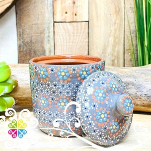 May include: Gray ceramic jar with a lid, both decorated with white, blue, orange, and yellow dots. The jar has a brown rim.