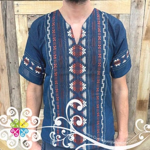 May include: A blue short-sleeved shirt with a V-neck and intricate red, white, and blue embroidery. The embroidery features geometric patterns and designs.