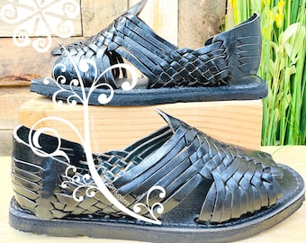 May include: A pair of black leather sandals with a woven design. The sandals are made of a soft, supple leather and have a comfortable fit.
