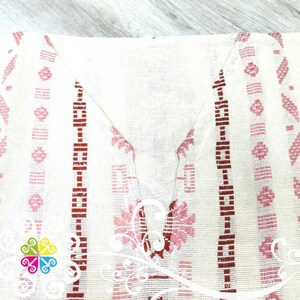 May include: White cotton fabric with pink and red embroidered geometric patterns. The fabric has a woven texture and a slightly sheer appearance.