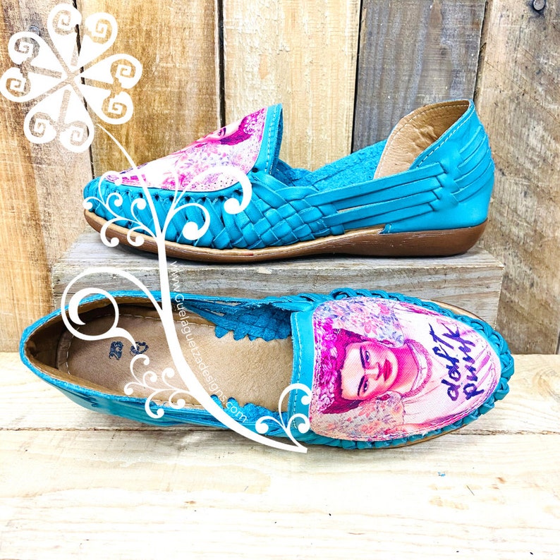 Pode incluir: Um par de sapatos de couro tecido azul turquesa com uma imagem de Frida Kahlo e o texto "Don't Pink" na ponta.